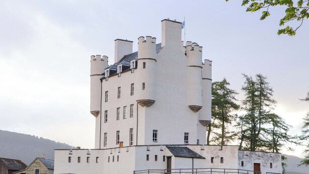 Un edificio simile a un castello, con numerose torri, un ingresso centrale e una recinzione tutt'intorno.