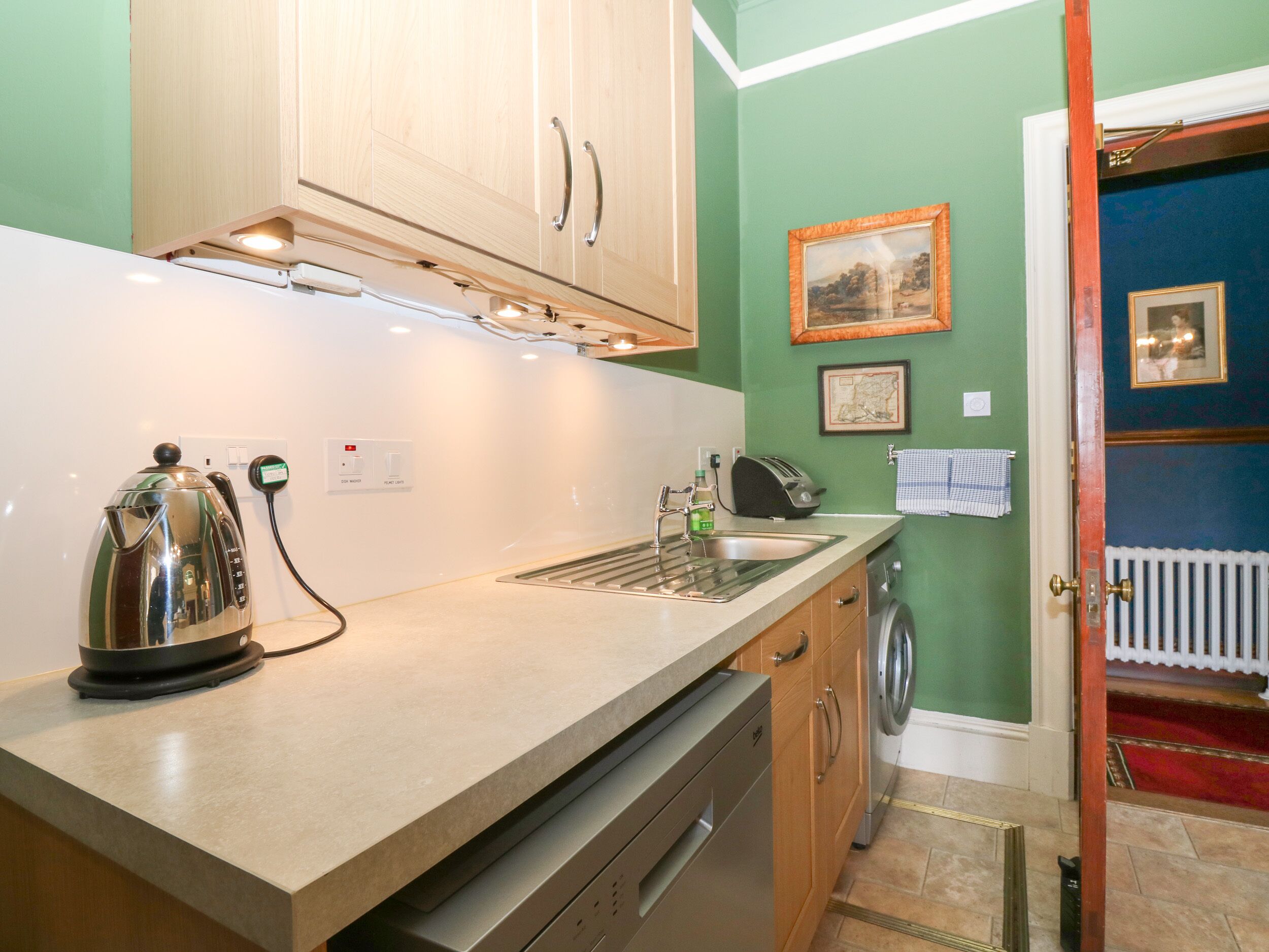 A compact kitchen with a kettle, toaster, and sink.