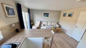 A compact living space with a kitchenette, a sofa, a coffee table, and a dining table. - Gecko Beach (Truro)