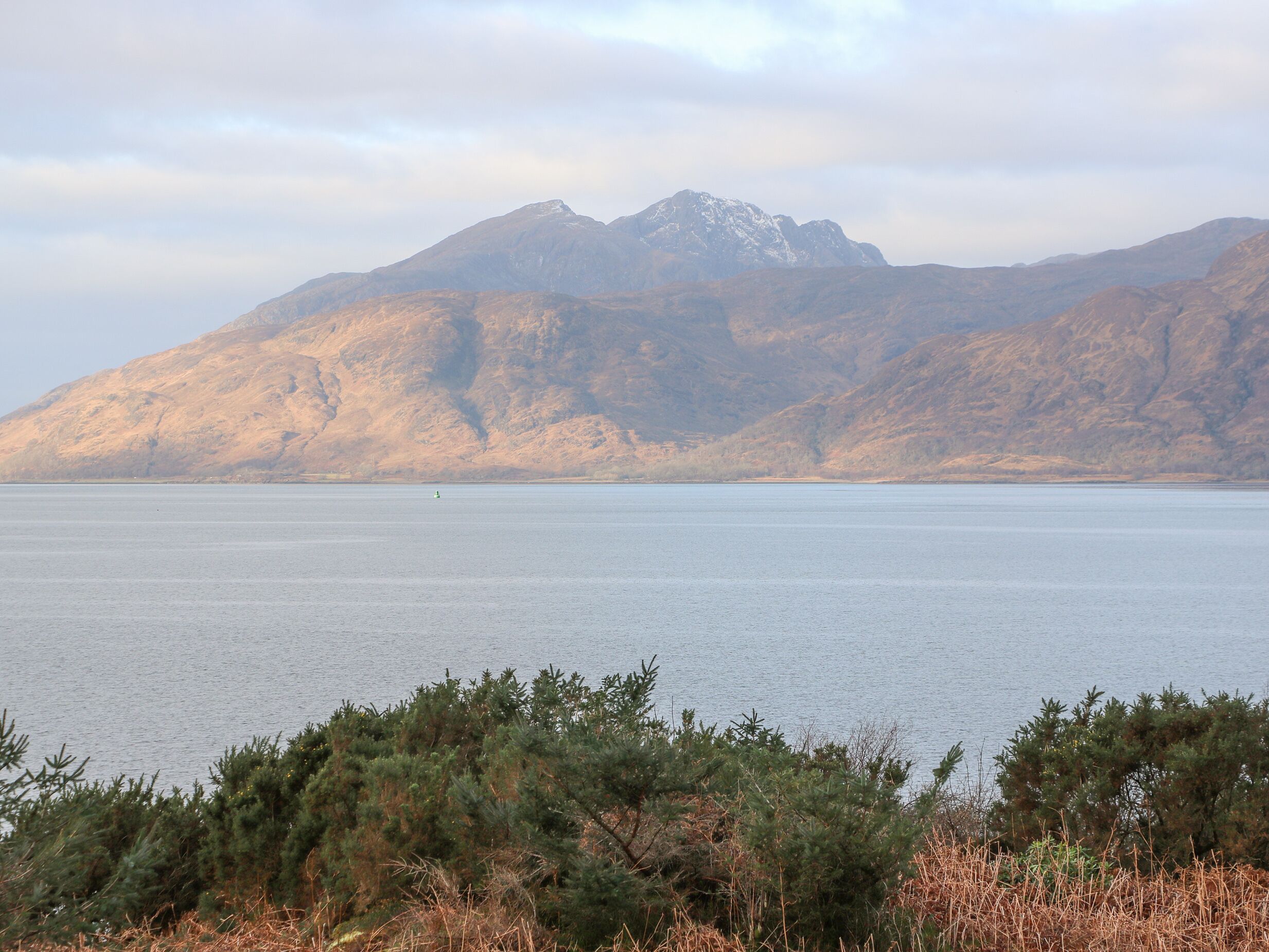 A mountain range with a body of water in the foreground.