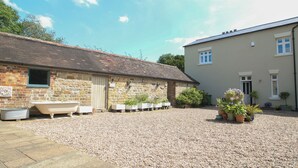 A stone building with a tiled roof and a modern building with a beige facade. - Foxholes Barn (Kidderminster)