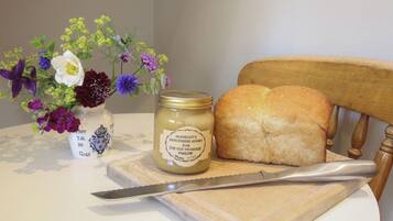 Ein Glas McKnight's Shropshire Honey, ein Laib Brot und ein Messer auf einem Holzschnittbrett.
