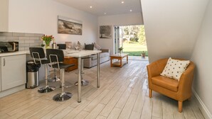 A modern kitchen with a dining area, a sofa, and a view of the outdoors. - Greenlawns (Burnham-on-Sea)