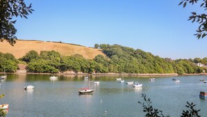 Ein ruhiger See mit mehreren Booten, umgeben von grünen Hügeln und Bäumen.