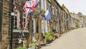 Une rangée de bâtiments traditionnels en pierre, décorés de drapeaux et de plantes en pot.