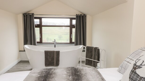 Une salle de bain avec une baignoire, une fenêtre avec des rideaux et un porte-serviettes.