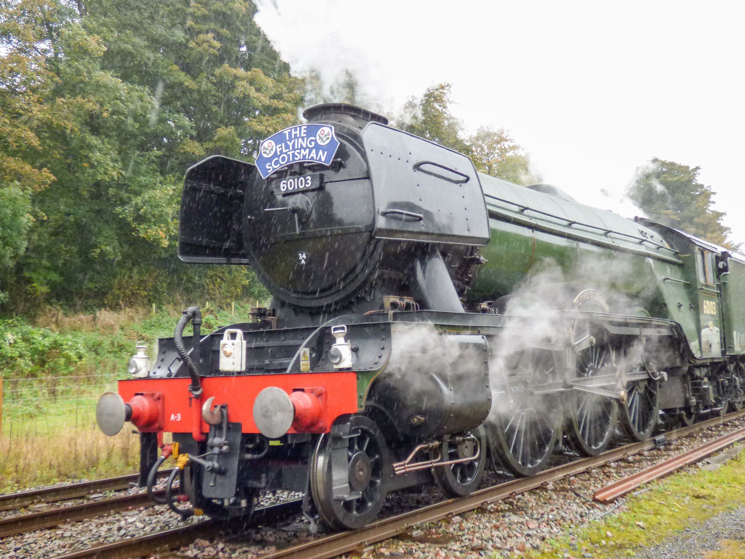 A steam locomotive with the number 60103, named "The Flying Scotsman," traveling on a railway track.