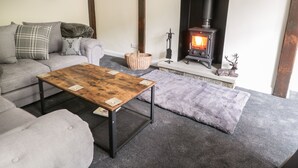 Un salon chaleureux avec une cheminée, un canapé, une table basse et un tapis.