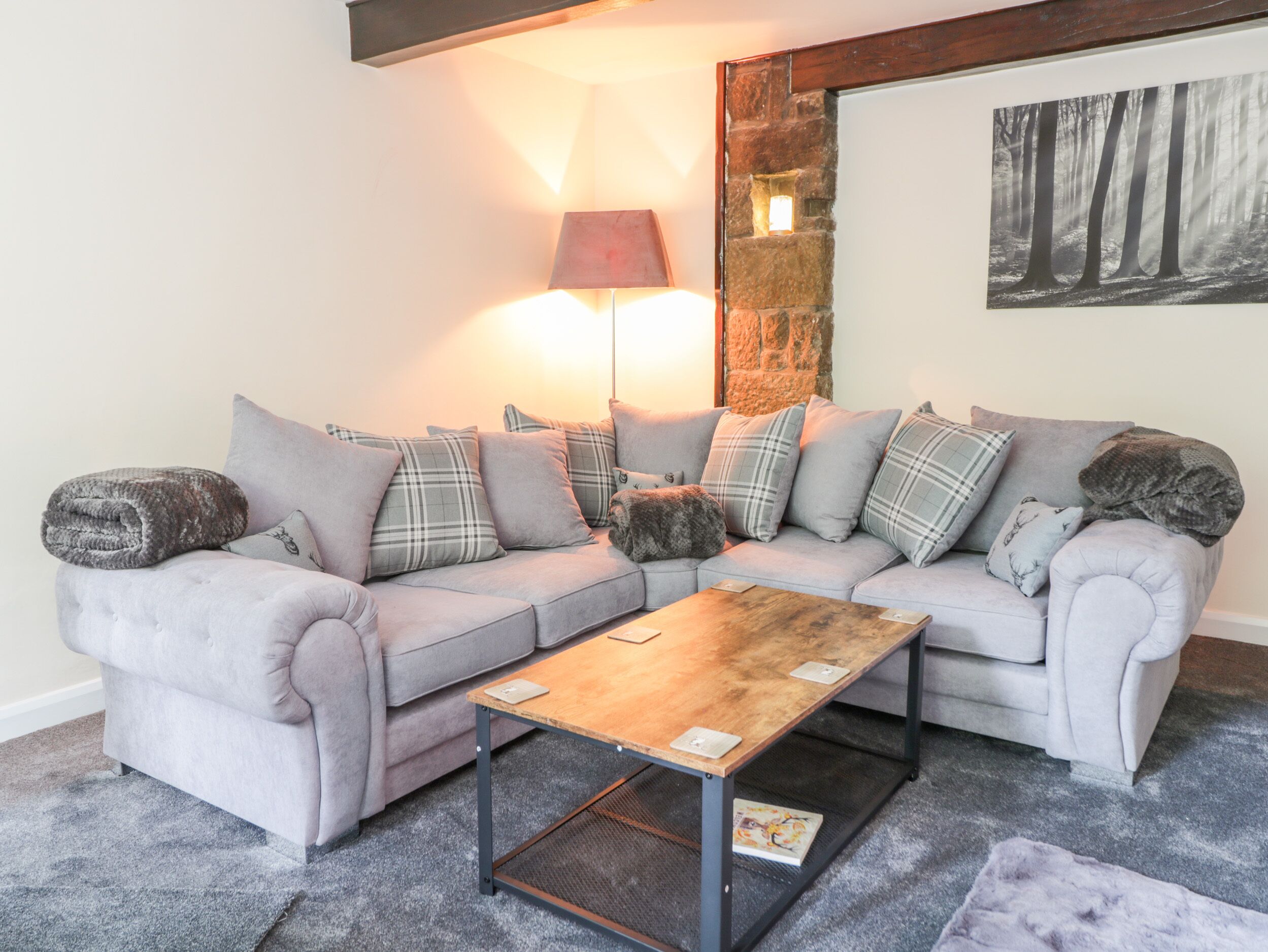 A living room with a grey sectional sofa, a wooden coffee table, and a stone accent wall.