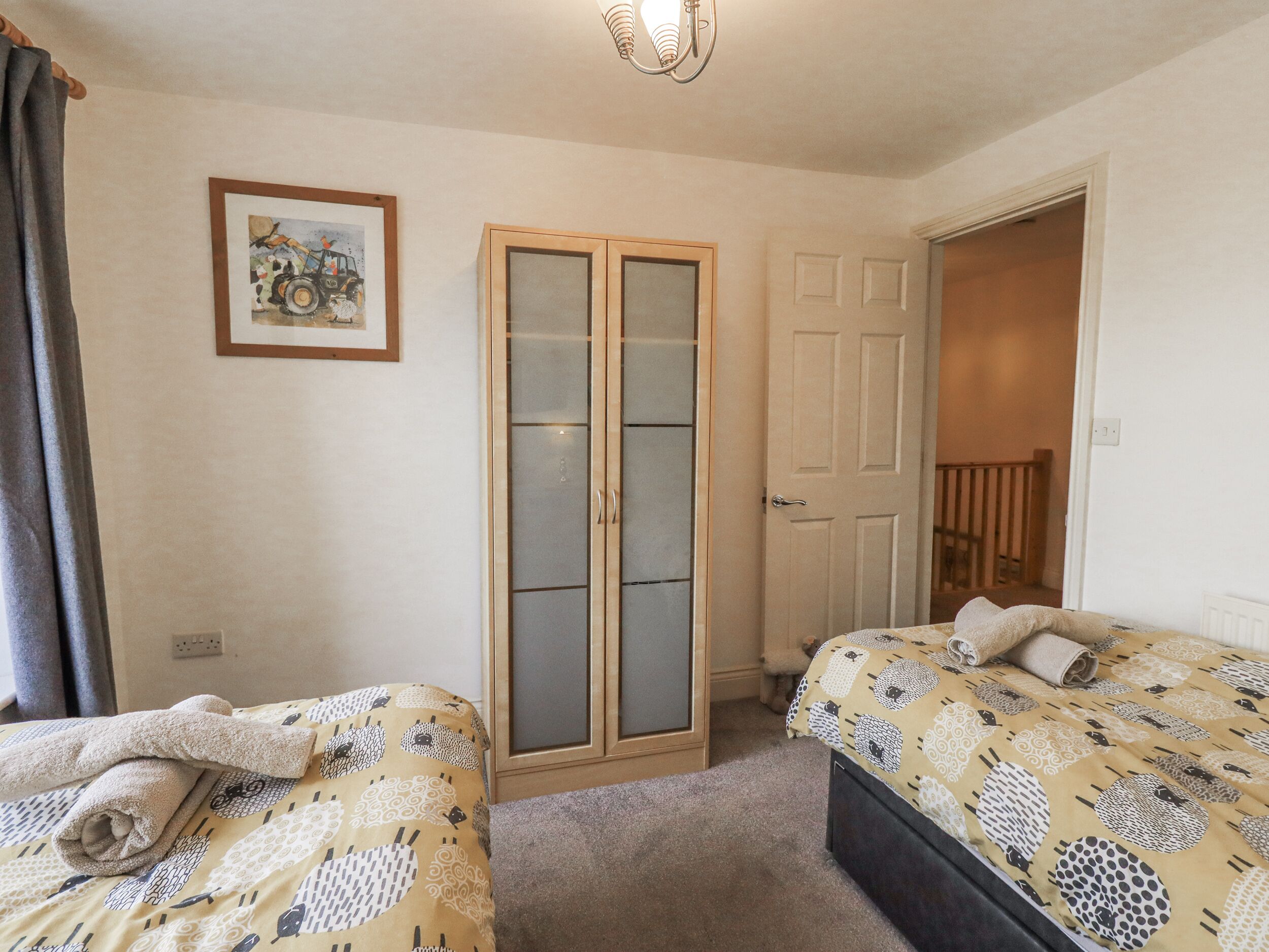 A bedroom with two beds, a wardrobe, a door, and a framed picture on the wall.