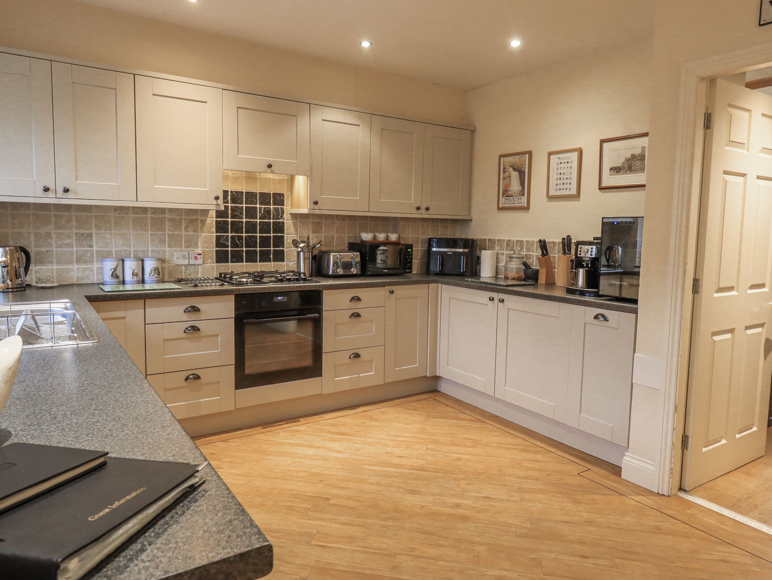 A modern kitchen with white cabinets, a granite countertop, and a wood floor.