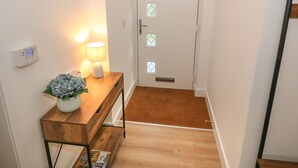 Un couloir avec une console en bois, une lampe et une plante en pot.