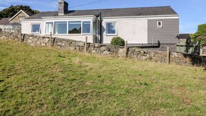 Une maison à deux étages avec un mur en pierre et une clôture en métal à l’avant.