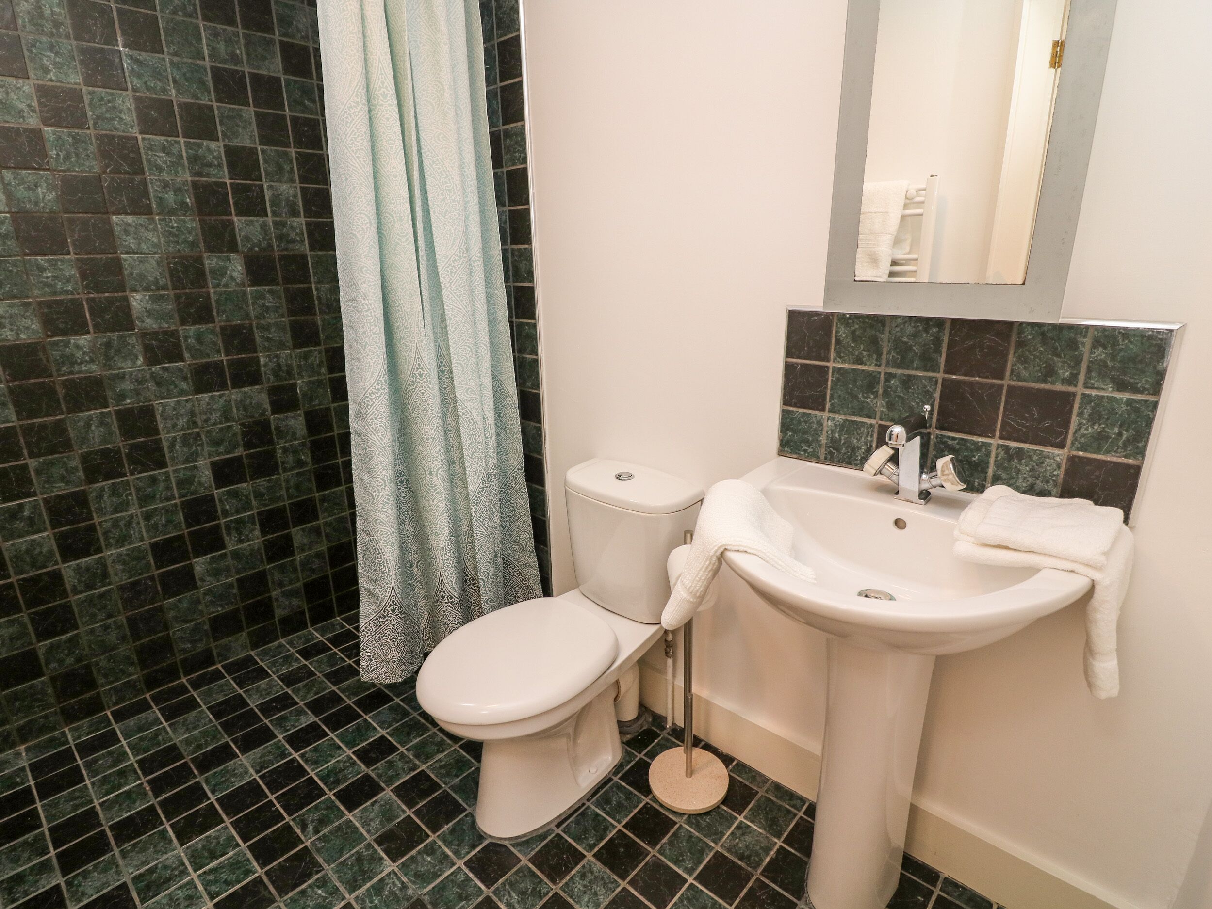 A bathroom with a toilet, sink, and shower curtain.