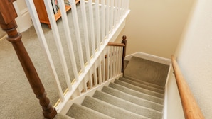 A carpeted staircase with wooden handrails and a white banister. - Westmorland Cottage (Grange-over-Sands)