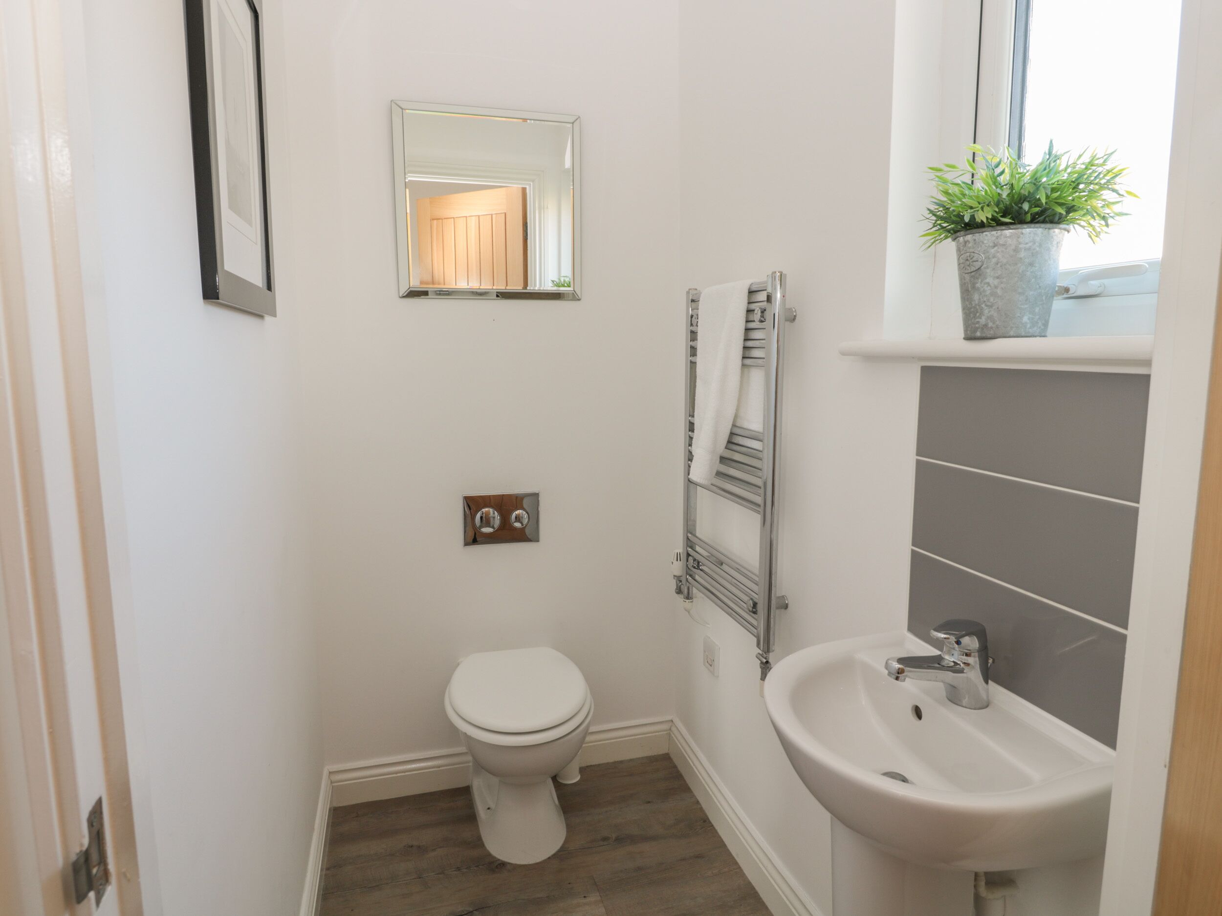 A small, clean bathroom with a toilet, a sink, a towel rack, and a mirror.