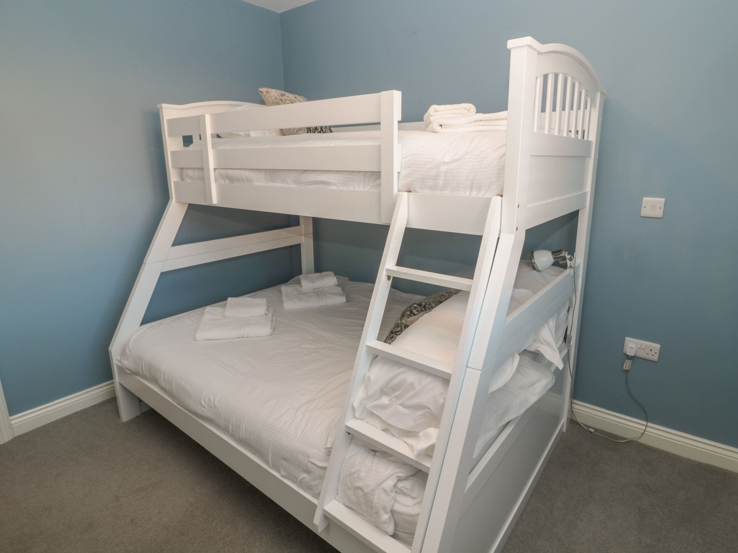 A bunk bed in a room with blue walls and a carpeted floor.