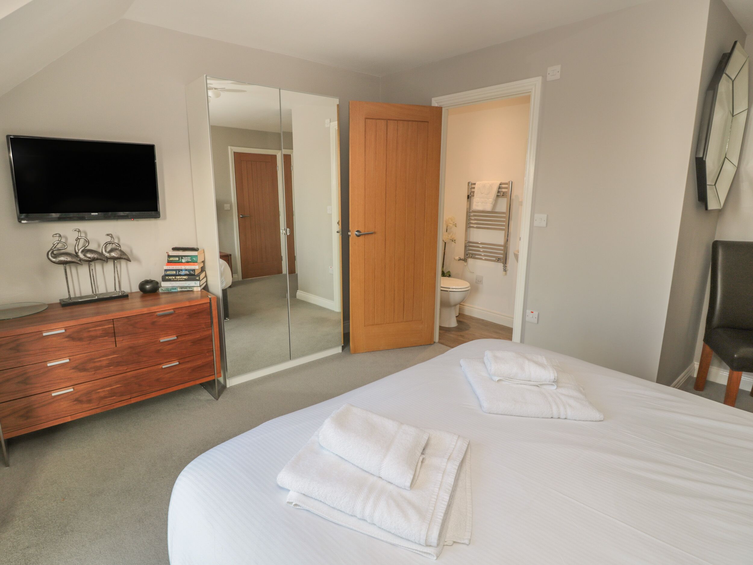 A bedroom with a bed, a dresser, a television, and a mirror.
