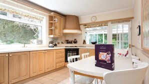 Una cocina con armarios de madera, encimera blanca, estufa y comedor con mesa y sillas.