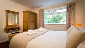 Un dormitorio con una cama grande, un armario de madera, un espejo y una ventana con cortinas.