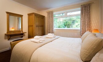 Un dormitorio con una cama grande, un armario de madera, un espejo y una ventana con cortinas.
