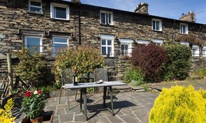 A stone house with a patio area featuring a table and chairs.
