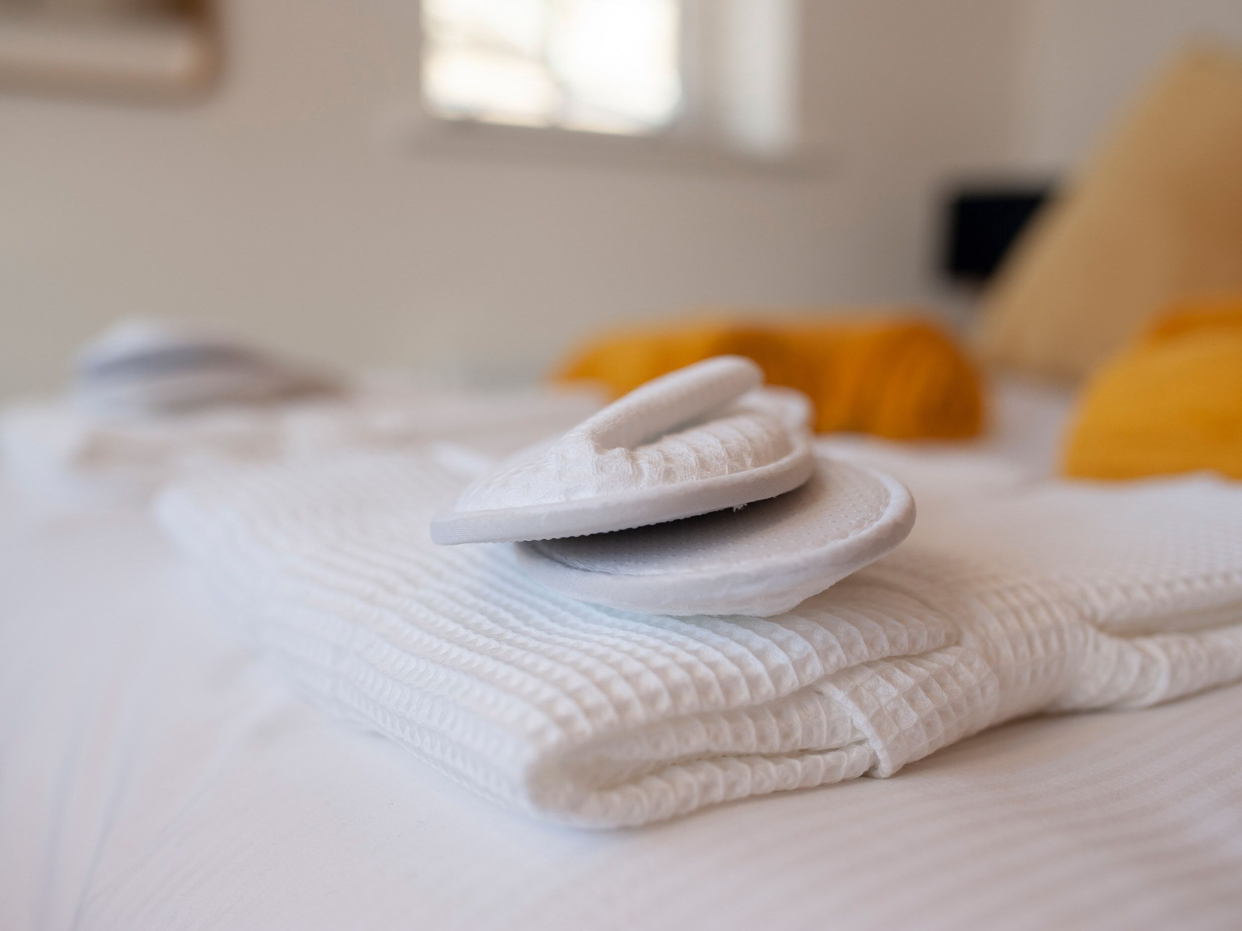 A neatly made bed with white linens and a folded towel.