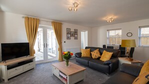 A modern living room with a flat-screen TV, a sofa, a coffee table, and a lamp. - Salt Bay (Whitby)