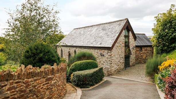 A stone building with a sloped roof, a small door, and a pathway leading to it. - Frogwell Chapel (Callington)