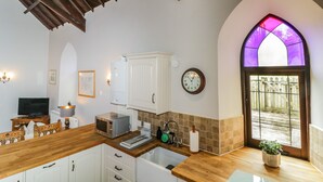 A kitchen with wooden countertops, white cabinets, a microwave, a sink, and a clock on the wall. - Frogwell Chapel (Callington)