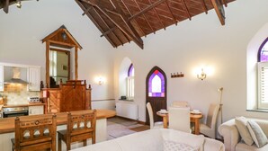 A cozy living area with a wooden ceiling, a dining table with chairs, a sofa, and a kitchen in the background. - Frogwell Chapel (Callington)