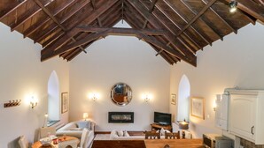 A cozy room with a wooden ceiling, a dining area with a table and chairs, a sofa, a television, and a kitchen area with cabinets and appliances. - Frogwell Chapel (Callington)
