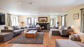 A spacious living room with a fireplace, two sofas, a coffee table, and a TV mounted on the wall. - Ecclerigg Garth (Windermere)