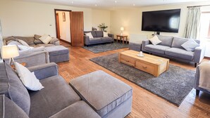 A modern living room with grey sofas, a wooden coffee table, and a large flat-screen TV. - Ecclerigg Garth (Windermere)