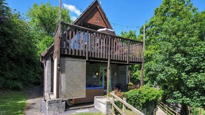 Eine Holzhütte mit einem Balkon, umgeben von üppigem Grün.
