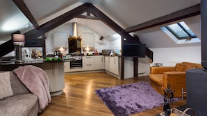 Un espacio habitable tipo loft con una cocina, un sofá, una mesa de centro y un televisor.
