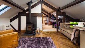 Un acogedor espacio tipo loft con vigas de madera a la vista, chimenea, sofá y comedor.