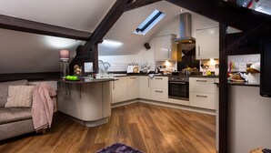 Cocina compacta con una isla central, armarios blancos y horno integrado.
