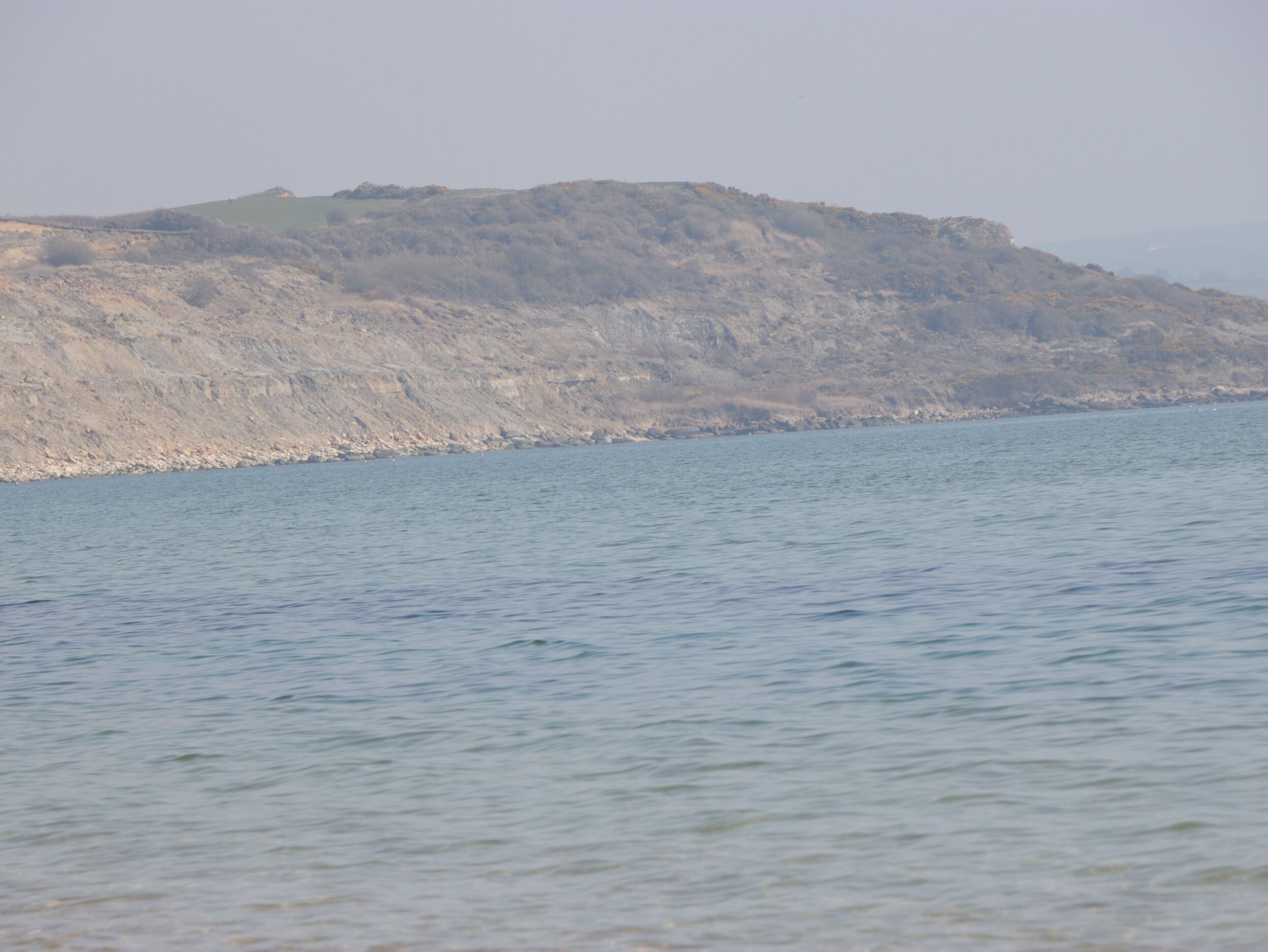 Un paysage côtier avec une falaise rocheuse et une mer calme.