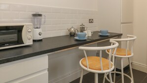 A kitchen with a microwave, blender, kettle, and bar stools. - Sea Peeps (Paignton)