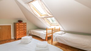 A bedroom with two beds, a wooden dresser, and a skylight. - Sea Peeps (Paignton)