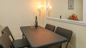 A dining area with a table, chairs, a bottle of wine, and glasses. - Sea Peeps (Paignton)