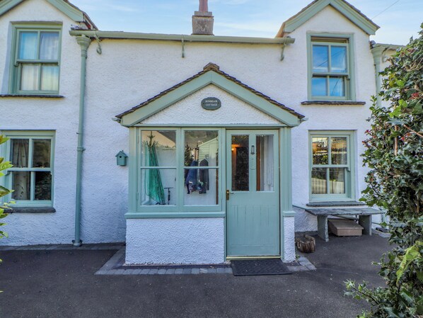 A cottage with a small porch, a door, and a window.