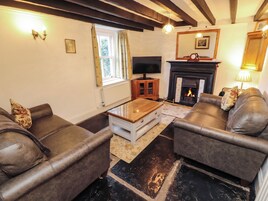 A living room with leather sofas, a television, a fireplace, and a wooden coffee table.