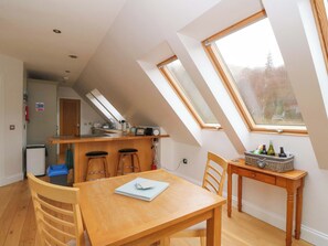 A kitchen with a counter, stools, and a dining table with chairs.