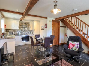 A modern kitchen with white cabinets, a dining area with a table and chairs, and a staircase leading to another level.
