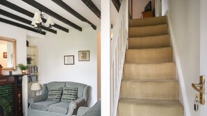 Una sala de estar con chimenea, un sofá y una escalera.