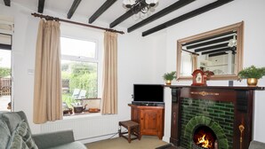 Una sala de estar con chimenea, televisor y ventana con cortinas.