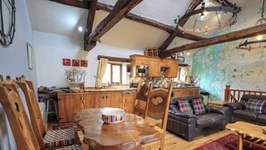 A rustic interior with a wooden dining table, chairs, a leather sofa, and a kitchen area. - Tullythwaite Garth (Kendal)