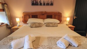 A neatly made bed with two pillows, a headboard, and two bedside lamps. - Tullythwaite Garth (Kendal)